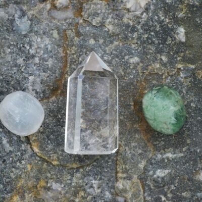 Assorted healing crystals including quartz on a textured stone surface.