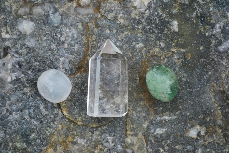 Assorted healing crystals including quartz on a textured stone surface.