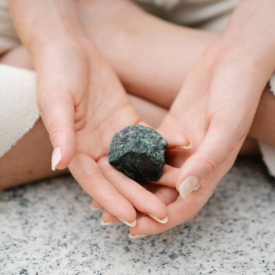 Close-up of hands gently holding a healing gemstone during meditation.