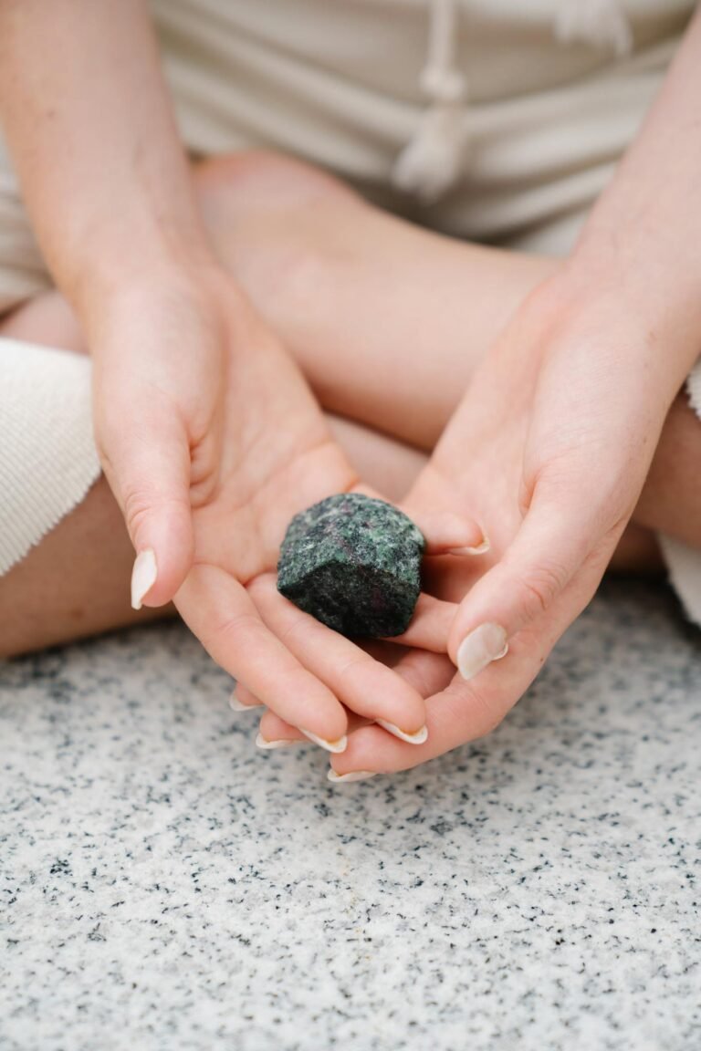 Close-up of hands gently holding a healing gemstone during meditation.