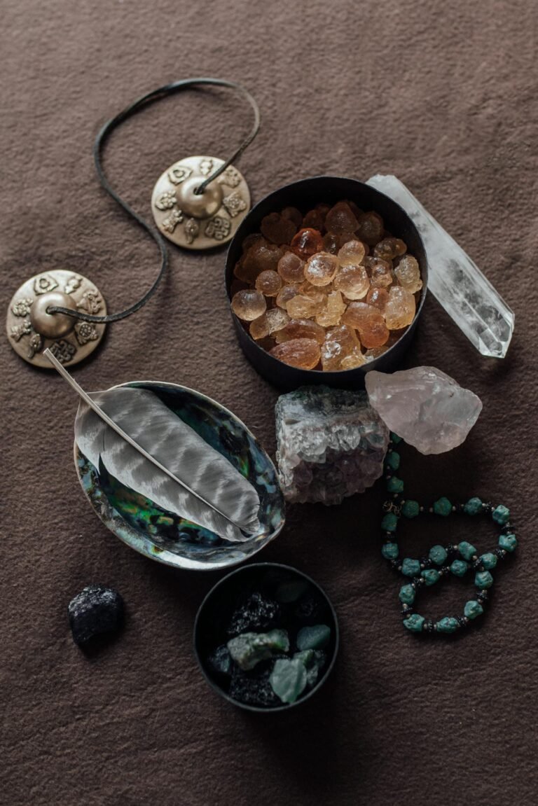 Flat lay of healing crystals, tingsha cymbals, and feathers for spiritual practices.