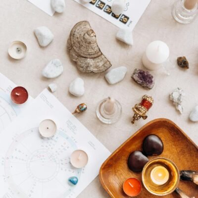 Flat lay of spiritual items including candles, crystals, and astrology charts for meditation.